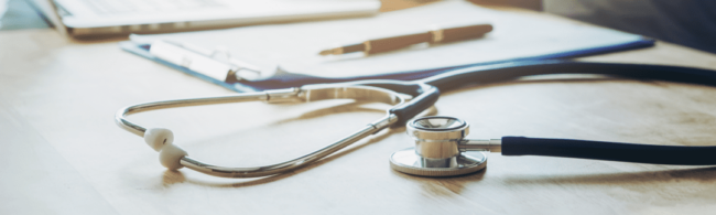 Stethoscope with clipboard and pen on desk